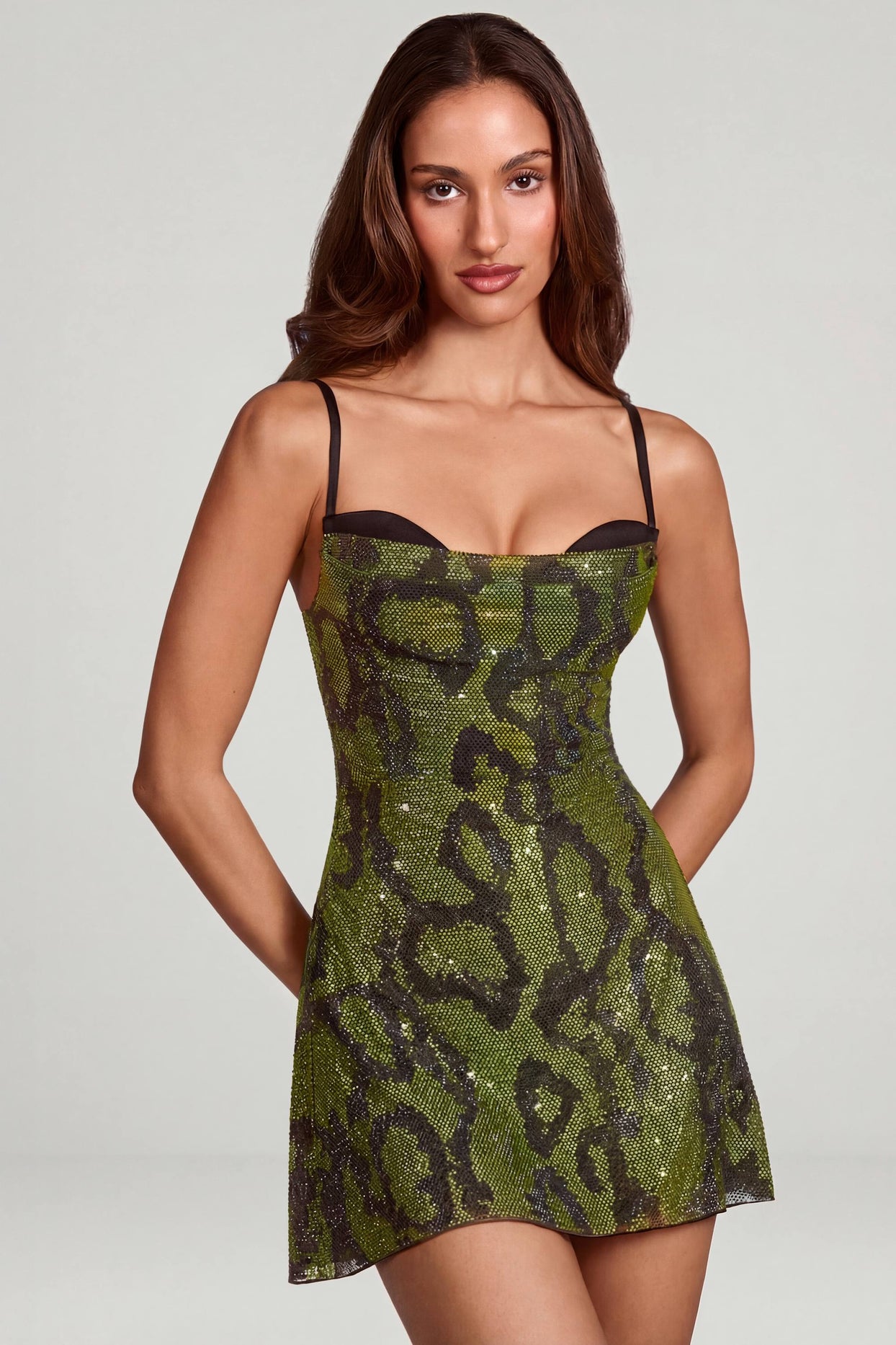 Oh Polly model Yasmin wearing the Dianora Mini Dress in Green Snake Square Hotfix fabric perfect for a cocktail event