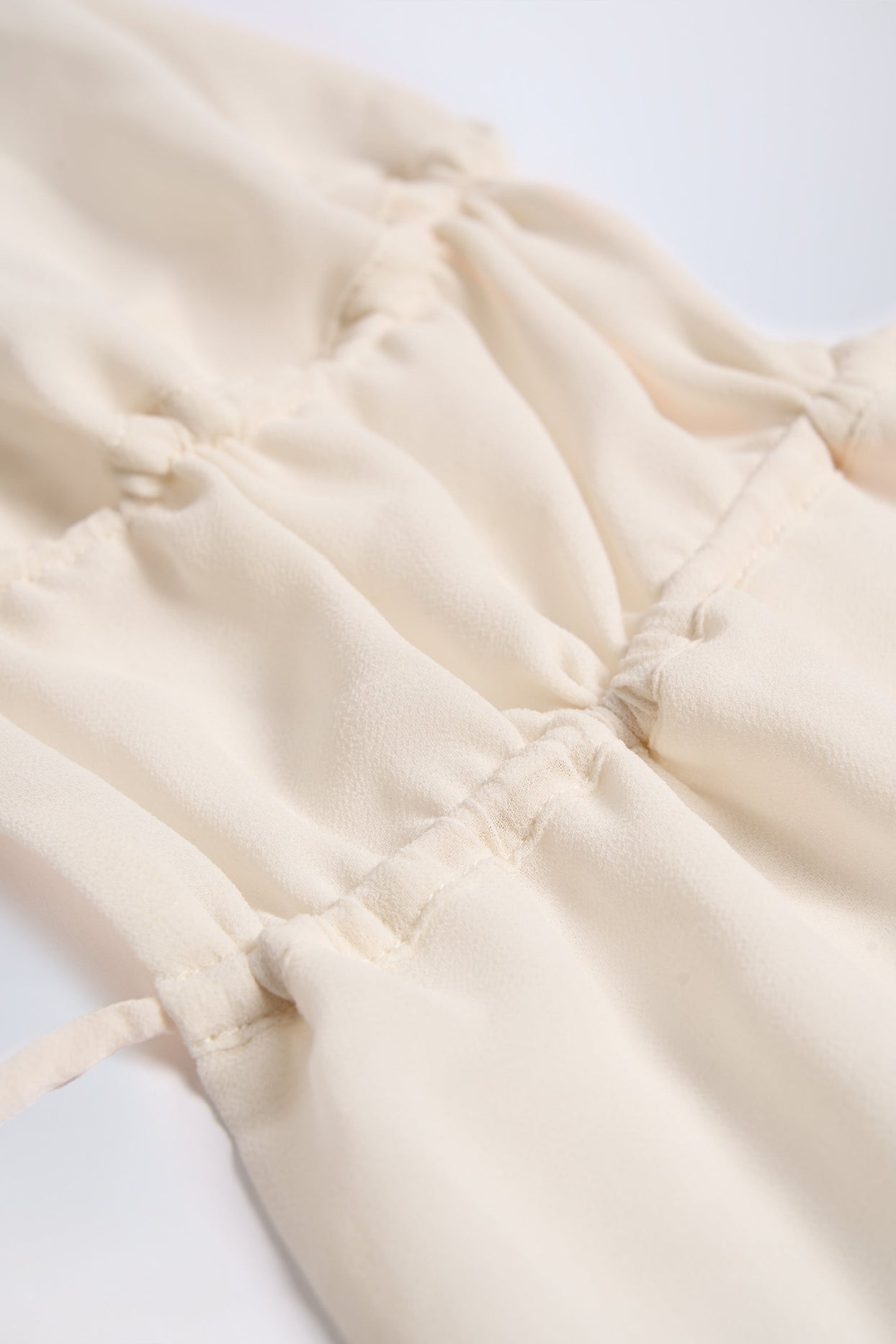 بلوزة قصيرة شبه شفافة مكشكشة، بفتحة رقبة دائرية، بلون عاجي