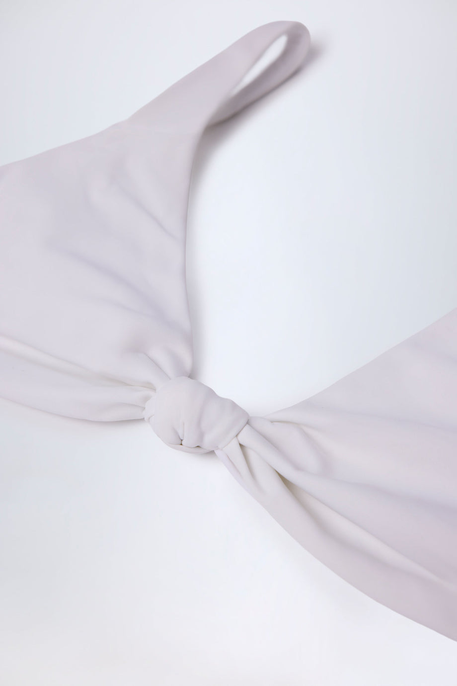 الجزء العلوي من بيكيني بتفاصيل عقدة باللون الأبيض